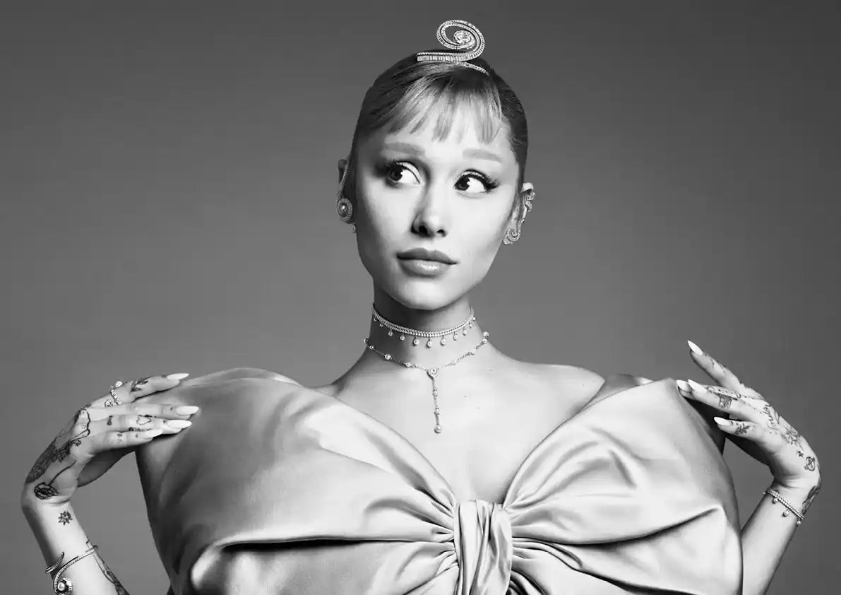 Una donna con un'acconciatura unica, indossa una maglia con un grande fiocco e intricati gioielli per le mani.